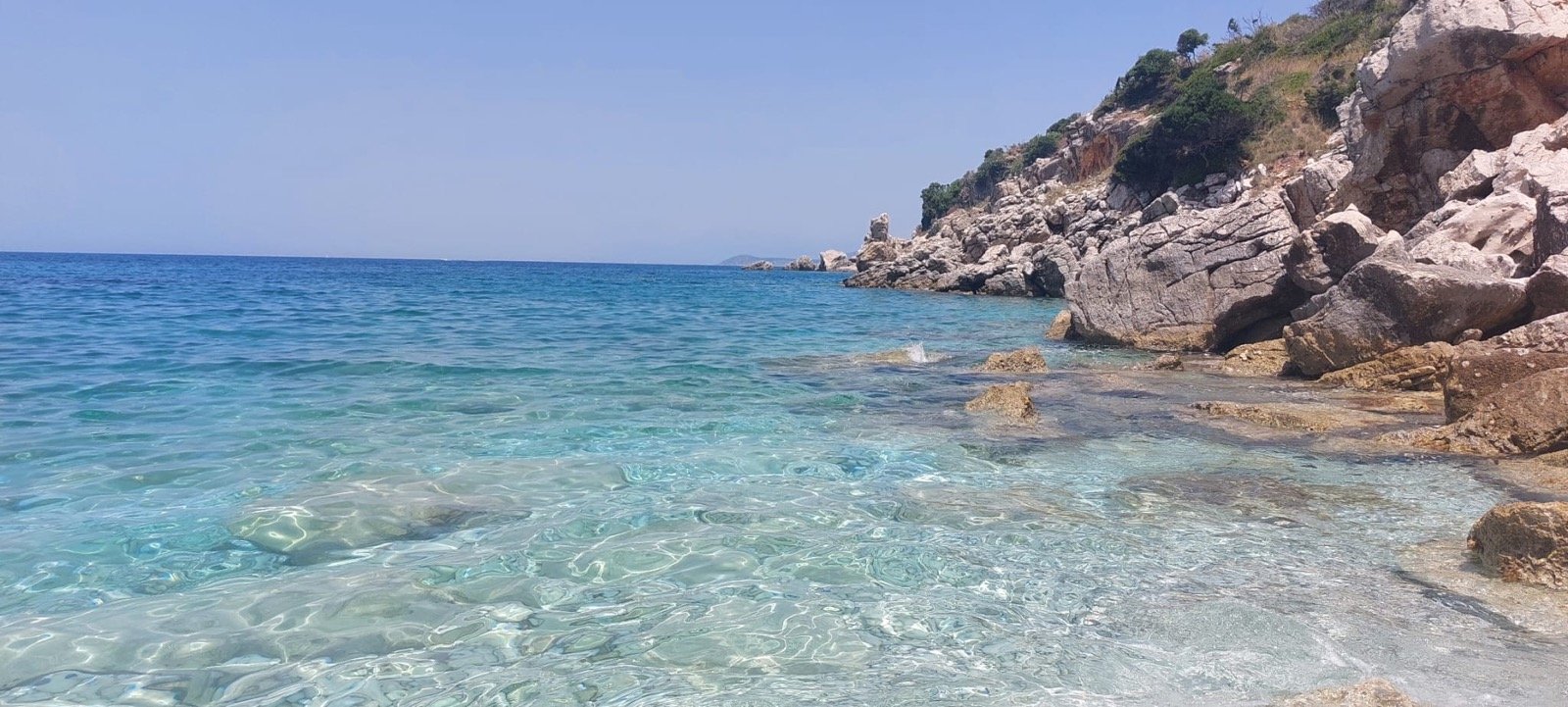 Beautiful turquoise water beach scene with rocky cliffs, clear shallow water, and limestone formations